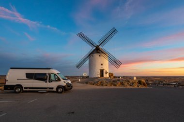 Gün batımında La Mancha 'daki tarihi İspanyol yel değirmenlerine hayran kalmış bir karavan.