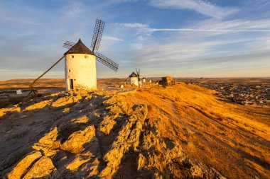 Geleneksel yel değirmenleri, İspanya 'nın La Mancha kentindeki şehre tepeden bakan canlı bir gökyüzüne karşı.
