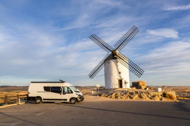 İspanya, Consuegra 'da mavi gökyüzünün altında, tarihi bir değirmenin yanına park edilmiş bir karavan.