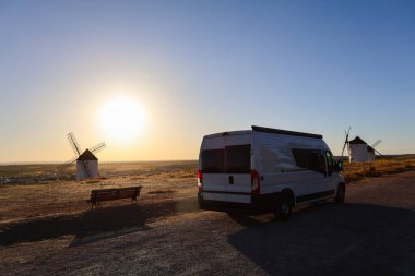 Gün batımında Mota del Cuervo 'daki yel değirmenlerine bakan bir karavan.