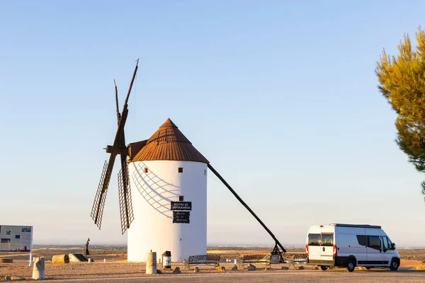 Beyaz İspanyol yel değirmeni gün batımında La Mancha 'da bir karavanın yanında duruyor.