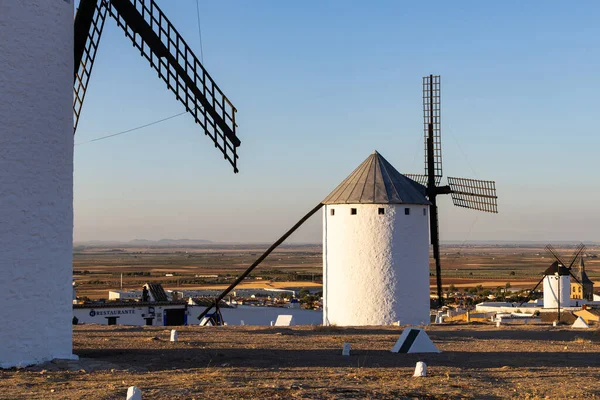 Kuru bir tepede beyaz yel değirmenleri ovalara bakan ve temiz bir gökyüzünün altındaki bir kasaba