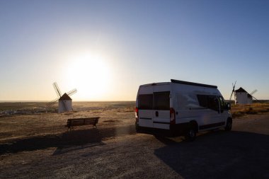 Mota del Cuervo 'da güzel bir günbatımında ikonik yel değirmenlerine hayran olan bir karavan park etti.