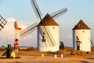 İspanya, La Mancha 'da tarihi yel değirmenlerinin ve Don Kişot heykellerinin yanında duran kadın.