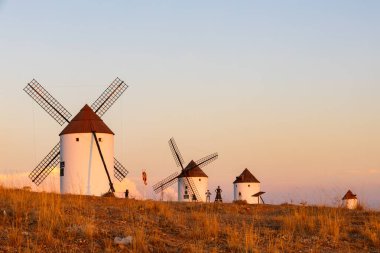 Sıcak bir gökyüzünün altında, enerji mirası ve turizmi temsil eden tarihi yel değirmenleri grubu.