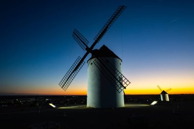 İspanya 'nın Mota del Cuervo şehrinde renkli bir alacakaranlık gökyüzüne karşı dikilen geleneksel İspanyol yel değirmeni
