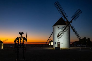 Don Kişot heykelinin silueti La Mancha 'daki tarihi yel değirmenlerinin önünde duruyor.