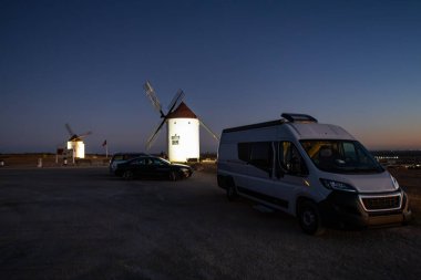 Kamp aracı, İspanya 'nın Mota del Cuervo şehrinde alacakaranlıkta tarihi değirmenlerin yakınına park edilmiş.