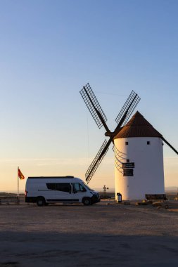 Tarihi bir İspanyol yel değirmeninin yanına park edilmiş karavan, La Mancha 'daki seyahat ve macerayı simgeliyor.