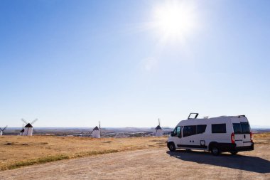 İspanya, La Mancha 'da açık bir gökyüzünün altında yel değirmenlerine ve manzaraya bakan bir karavan.