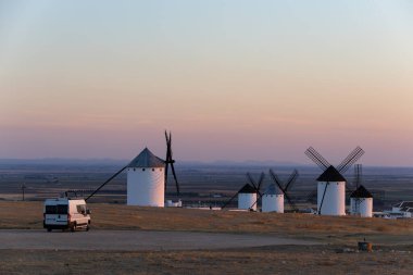 La Mancha 'daki tarihi yel değirmenlerinin yakınına park etmiş bir karavan renkli bir akşam göğüne karşı.