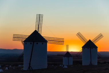 Bir tepede duran tarihi yel değirmenleri, La Mancha 'da alacakaranlıkta geleneksel mimariye ev sahipliği yapıyor.