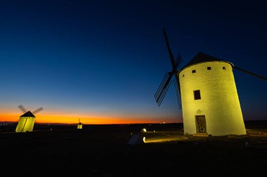 Tarihsel İspanyol yel değirmenleri alacakaranlıkta parıl parıl parlıyor. Klasik bir La Mancha manzarasını sunuyorlar.