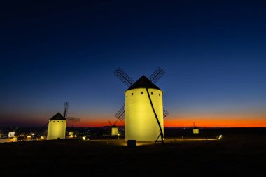 İspanya 'nın Campo de Criptana şehrinde günbatımı gökyüzünde parlayan tarihi yel değirmenleri