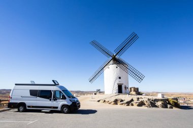 Tarihi bir yel değirmeninin yanına park edilmiş bir karavan İspanya 'da yol gezisini ve minibüs hayatını simgeliyor.