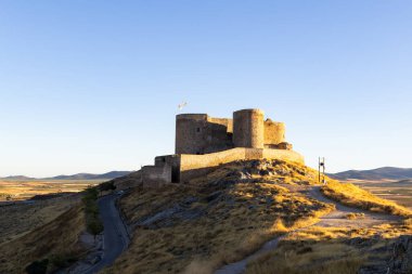 Antik Consuegra kalesi bir tepenin üstünde duruyor, sabah sıcacık ışıklarıyla aydınlanıyor.