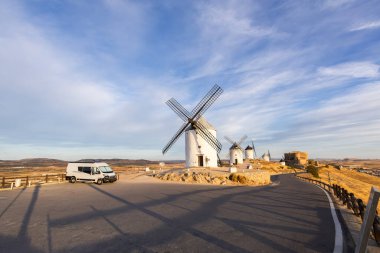 Geleneksel İspanyol yel değirmenlerinin ve şatosunun yakınına park edilmiş bir karavan, seyahat ve tarih sergileniyor.