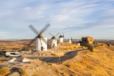 Günbatımında İspanya, Consuegra 'da bir tepenin üzerinde duran bir karavan ve yel değirmenleri.