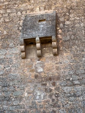 Eski bir taş duvardan yansıyan, mimari ayrıntıları ve dokuları gösteren bir maksikolasyon.