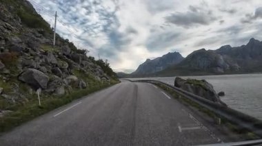 Norveç 'in Lofoten Adaları' ndaki dramatik dağlarla manzaralı bir sahil yolu boyunca giden bir karavan.