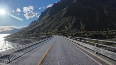 Karavanın bakış açısı muhteşem bir Norveç fiyordunda dolambaçlı bir yolda bir köprüden geçiyor.