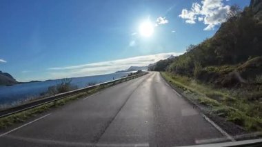 Norveç, Lofoten Adaları kıyısı boyunca güneşli bir yol gezisi, bir karavan panelinden görüldü.