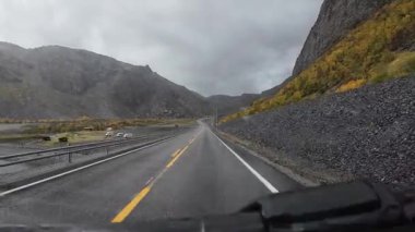 Bir kampçıdan gelen POV sonbaharda Nordkapp 'a doğru dolambaçlı bir dağ yolunda ilerliyor.