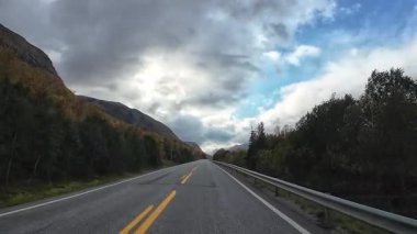 Kuzey Norveç 'in dağlık arazisi boyunca boş bir asfalt yolda ilerleyen bir bakış açısı