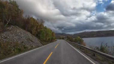 Norveç 'te sonbahar manzarası boyunca virajlı bir yolda bir karavanı sürerken çekilmiş bir fotoğraf.