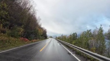 Kuzey Norveç 'te sonbahar manzarası boyunca ıslak asfalt bir yol boyunca karavan yolculuğu