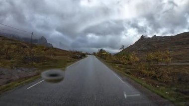 Norveç 'in Senja şehrinde bulutlu bir sonbahar gününde ıslak bir yolda araba sürerken çekilmiş bir bakış açısı