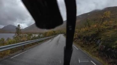 Karavanın bakış açısı Norveç, Senja 'nın sonbahar manzarası boyunca ıslak bir yolda sürüyor.