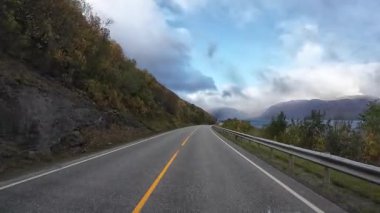 Norveç 'in kuzeyinde sonbahar boyunca manzaralı bir fiyort yolunda bir karavanı sürmek