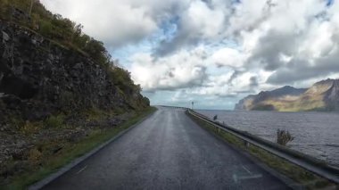 Norveç 'teki Senja adasının dramatik kıyı şeridi boyunca ıslak bir yolda araba süren bakış açısı