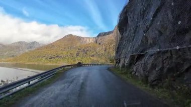 POV Norveç 'in Senja adasındaki fiyort boyunca virajlı bir yolda ilerliyor ve bir tünele giriyor.