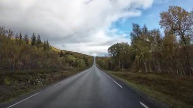 Norveç 'in Senja kentinde sonbahar boyunca boş bir yolda giden pitoresk bir karavan manzarası.