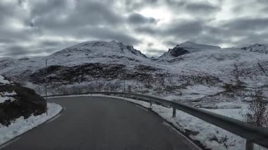 Kıvrımlı bir dağ yolunda kar manzarası olan bir aracın manzarası