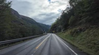 Sürücünün bakış açısı Norveç 'in dağları ve vadileri boyunca manzaralı bir yolda gidiyor.