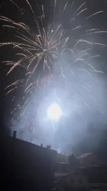 Şehrin siluetinin üzerindeki karanlık gökyüzünü aydınlatan parlak havai fişekler.