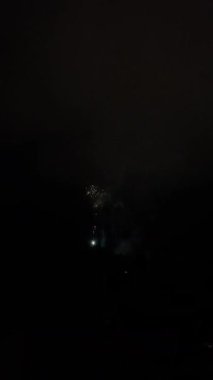 Gece vakti havai fişekler, parlak patlamalar, kıvılcımlar ve beyaz dumanlarla karanlık gökyüzüne karşı