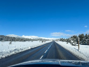 Occitanie 'deki karlı tarlalardan ve dağlardan geçen kış yolu