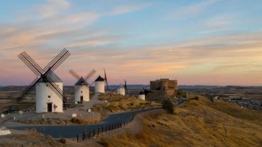 İspanya 'nın La Mancha kentindeki tarihi yel değirmenleri ve Consuegra kalesinde altın gün doğumu zamanı.