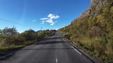 Norveç 'te dağları ve fiyortları olan manzaralı bir yolda bir karavanı sürerken çekilmiş bir fotoğraf.