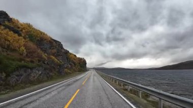 Karavan yolculuğu Norveç 'in manzaralı bir yolu boyunca dramatik bulutlu bir gökyüzünün altında bir gölün yanında
