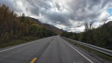 Alta 'da sonbahar Norveç manzarası boyunca boş bir asfalt yolda ilerleyen bir bakış açısı