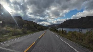 Norveç 'te uzak bir asfalt yolda giden karavanın etrafı çarpıcı doğa ve dağlarla çevrili.