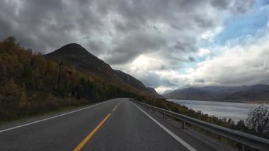 Norveç sonbahar manzarasında bir fiyort boyunca manzaralı bir yolda araba süren bakış açısı