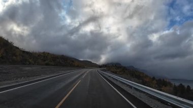 Norveç 'te bulutlu bir günde, kayalık bir arazide, asfalt bir yolda araba süren bir bakış açısı