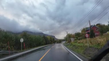 Norveç kırsalında ıslak asfalt yolda giden bir araçtan bakış açısı