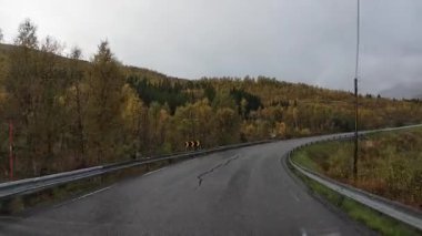 Senja 'da bulutlu bir sonbahar gününde, ıslak asfalt yolda bir karavanı sürmek...